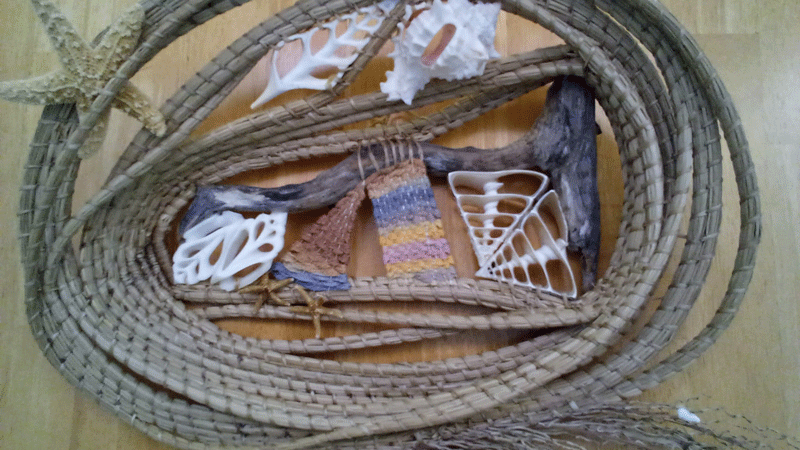 A woven basket with sea shells and seaweed.