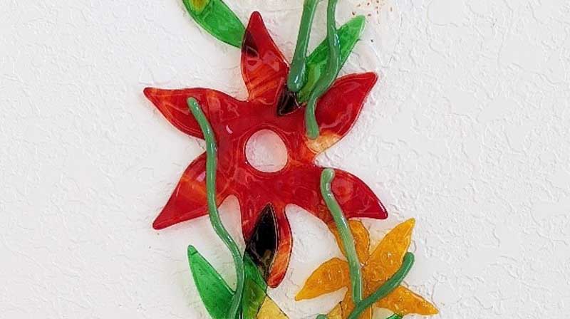 A wall hanging with red, yellow and green flowers.