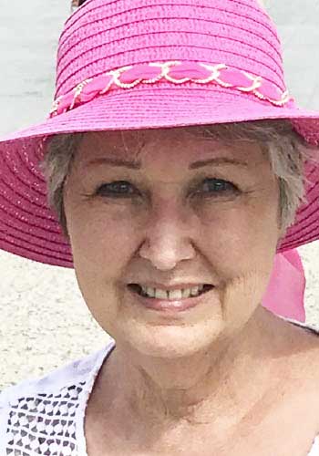 A woman in a pink hat smiling for a picture.