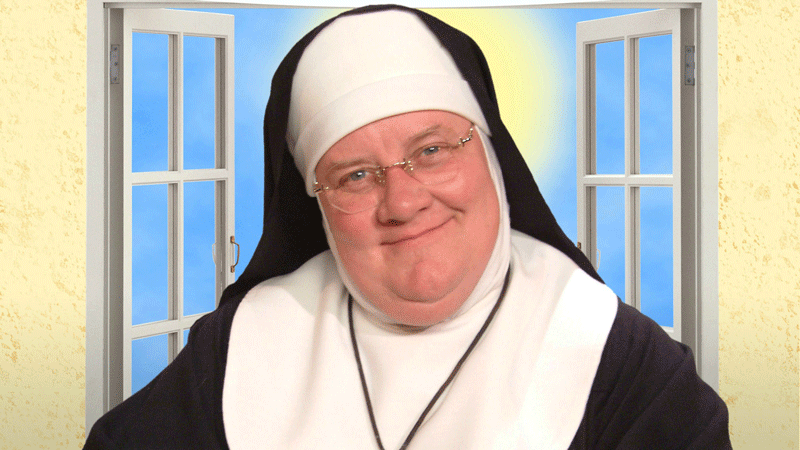 A nun smiling in front of a window.