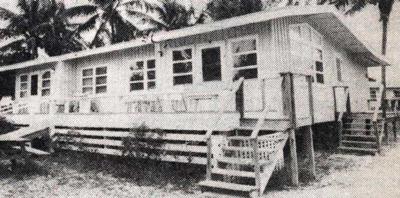 An old black and white photo of a house on the beach.