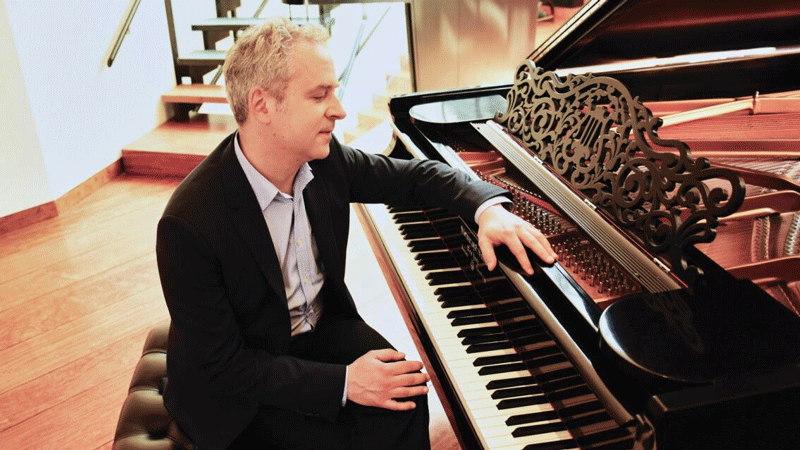 A man in a suit sitting at a piano.